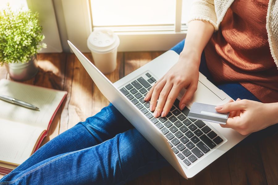 woman using computer while holding card